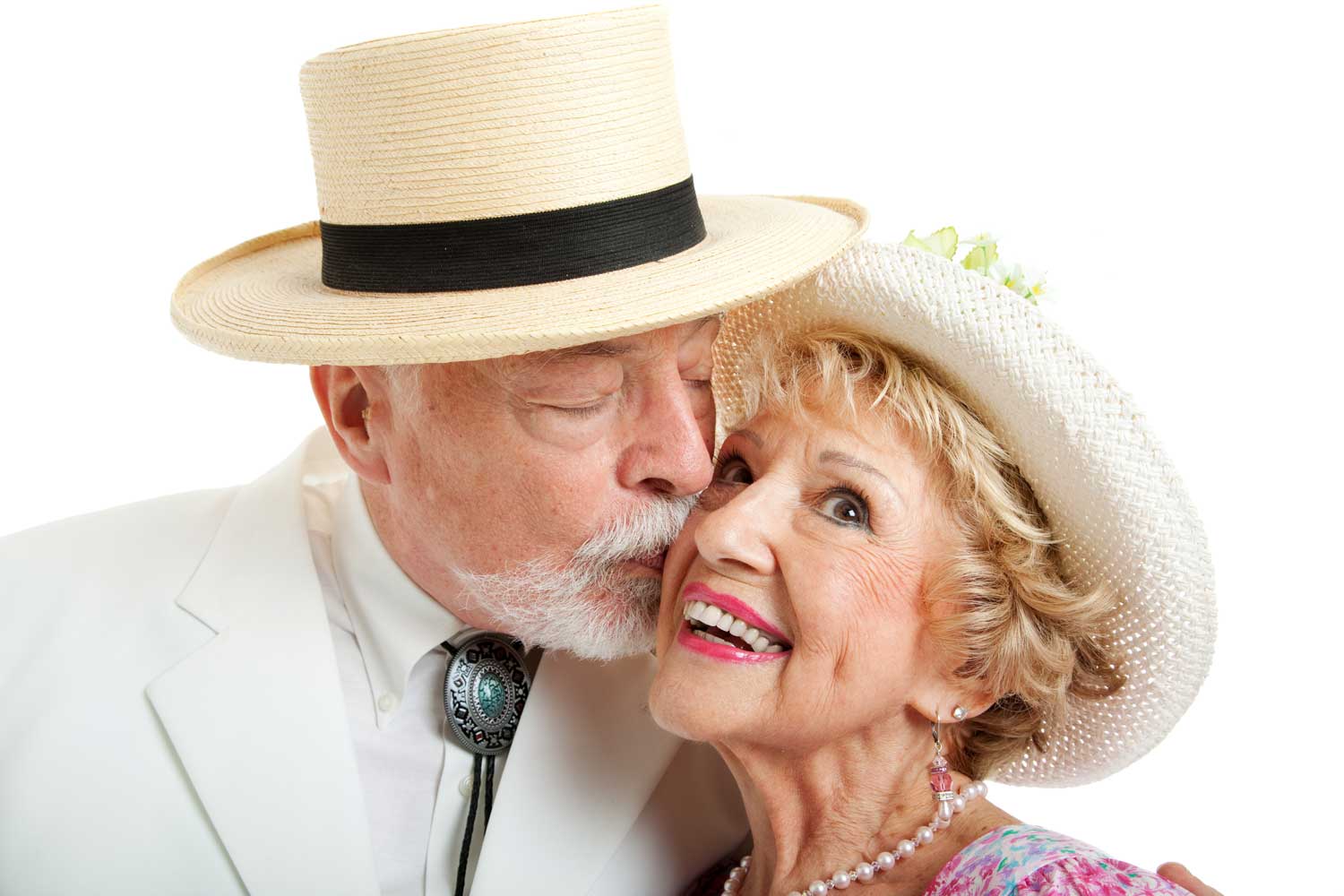 A smiling senior woman in Sunday dress kissed on the cheek by a senior man